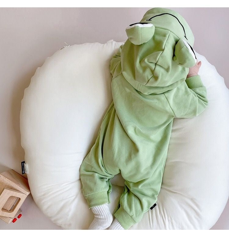 Adorable baby wearing a Frog Eyes hooded onesie with playful frog eye design, from Ju Ju Jam.