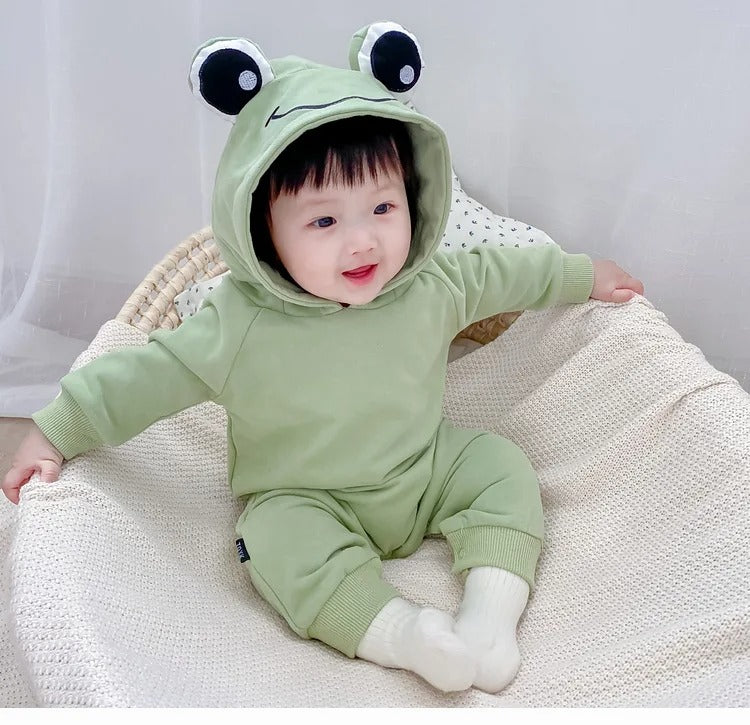 Charming baby wearing a Frog Eyes hooded onesie, featuring playful frog eyes, from Ju Ju Jam.