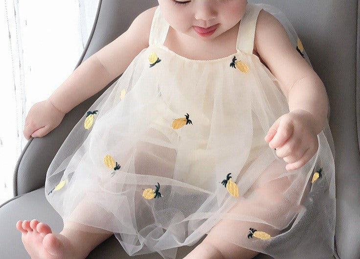 Adorable baby girl wearing a pineapple-themed frill romper dress from Ju Ju Jam.