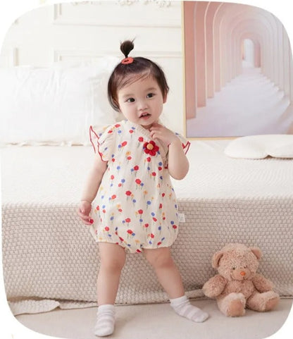 Adorable baby girl wearing a romper with a red flower detail, available at Ju Ju Jam.